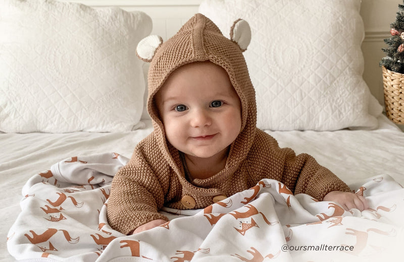 Baby wrapped in Kit & Kin cosy winter layers – celebrating baby’s first Christmas traditions