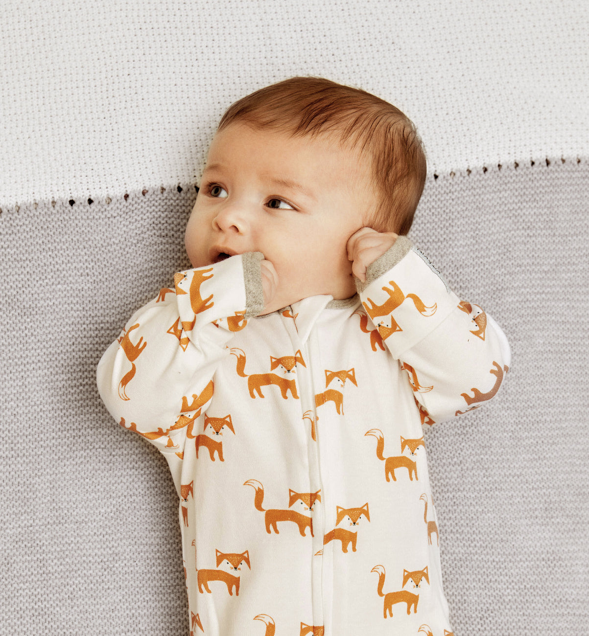 Baby lying on an eco-friendly organic cotton knitted baby blanket from Kit & Kin