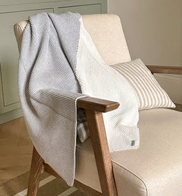 Our Kit & Kin unisex organic cotton baby blanket with knitted texture, draped over a nursing chair - the perfect finishing touch for your nursery.